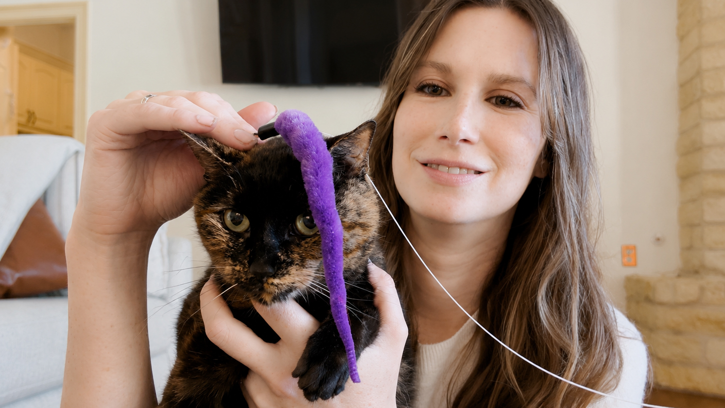 Young woman and tortie cat and cat wand toy